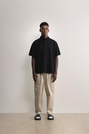 Standing model styling the black Kyneton Relaxed Fit Knit Polo A.B.C A BRAND COLLECTIVE boxy fit silhouette