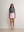 Model wearing the pink A.B.C A BRAND COLLECTIVE mini skirt paired with a grey knit top.