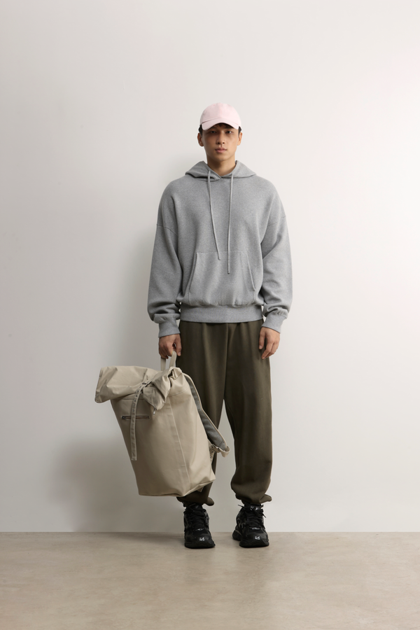 A.B.C A BRAND COLLECTIVE Kyneton Hoodie male model styling the grey knit with olive trousers and a travel bag 100% Good Earth Cotton
