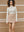Model wearing the ivory Mona Full Needle Rib Merino Wool Turtle Neck Top with a tan skirt A.B.C A BRAND COLLECTIVE sophisticated cold-weather dressing