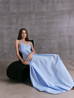 Seated model in blue MOREE dress by A.B.C A BRAND COLLECTIVE, fabric falls naturally, giving a soft and easy silhouette.
