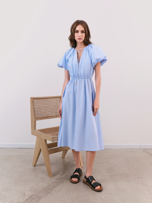 A feminine blue silhouette balancing romantic volume with modern minimalist tailoring.