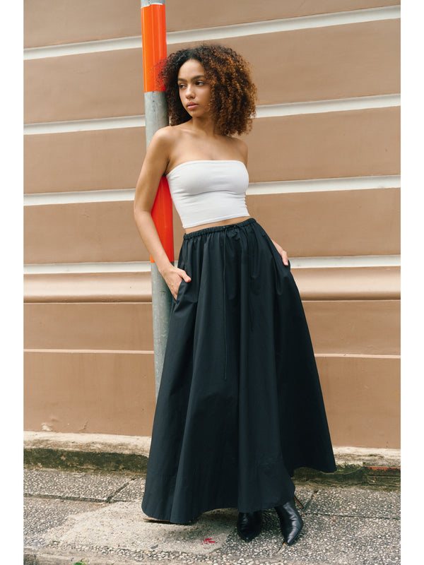 Standing model styling the black Moree Cotton Poplin Maxi Skirt with drawstring waist A.B.C A BRAND COLLECTIVE timeless elegance