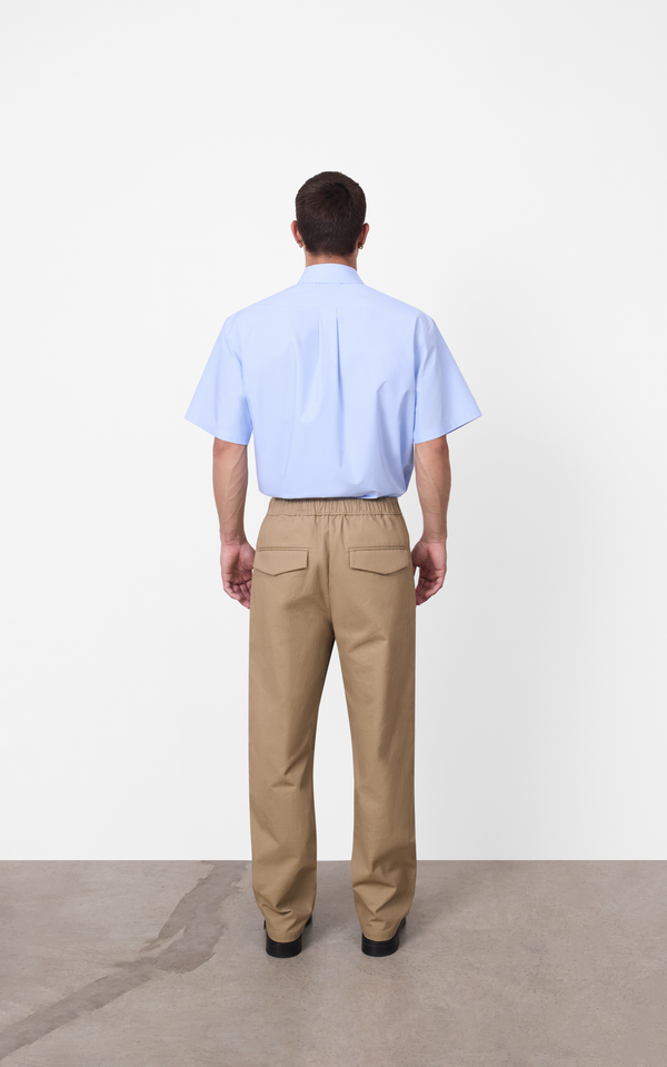 Close up of a neat elastic waistband and functional side hand pockets on relaxed beige trousers by A.B.C A BRAND COLLECTIVE