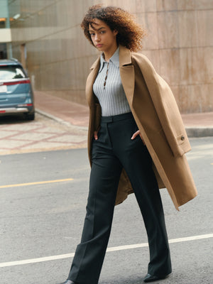 Lifestyle view of the black Croxton straight leg trousers by A.B.C A BRAND COLLECTIVE paired with a tan coat.