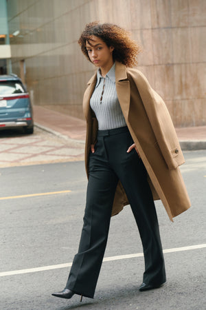 Lifestyle view of the black Croxton straight leg trousers by A.B.C A BRAND COLLECTIVE paired with a tan coat.