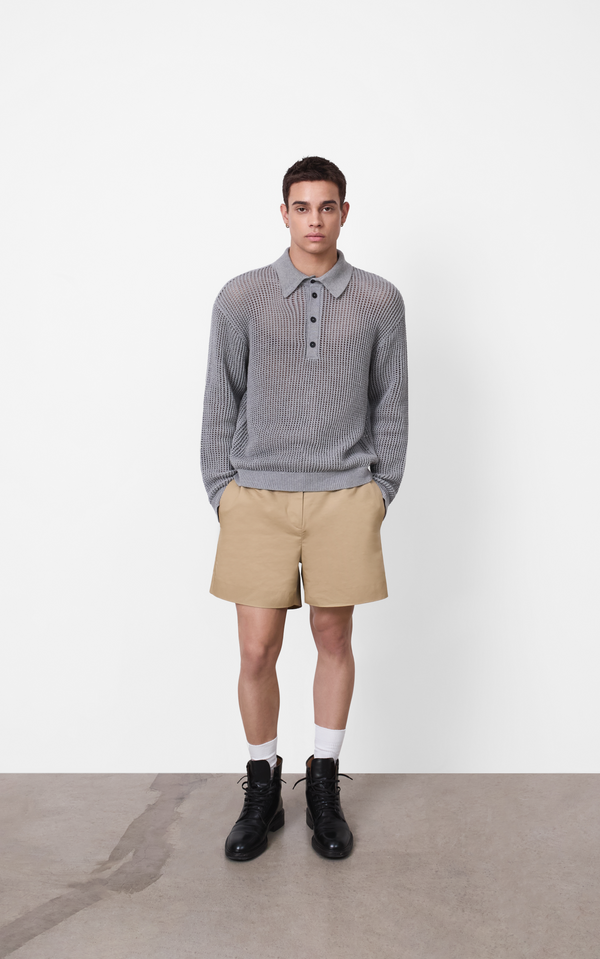 Man wearing a gray sweater, beige shorts, and black boots on a white background A.B.C - A Brand Collective