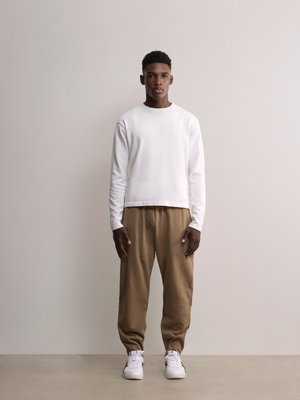 Model wears A.B.C white kyneton relaxed fit long sleeve crewneck knit top made of 100% Good Earth Cotton.