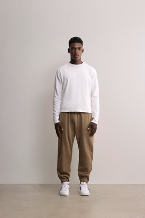 Model wears A.B.C white kyneton relaxed fit long sleeve crewneck knit top made of 100% Good Earth Cotton.